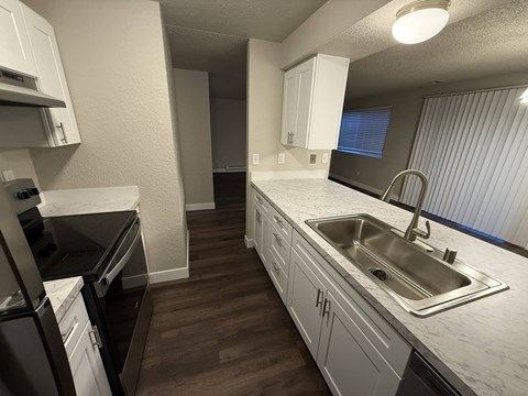 A kitchen with white cabinets and a stainless steel sink.