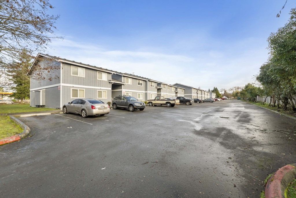 a row of apartment buildings with cars parked in a parking lot