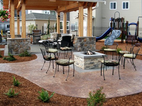 A patio with a fireplace and chairs.