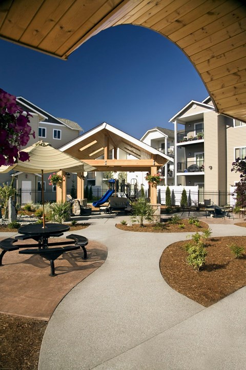 A playground area with a slide and picnic tables is surrounded by apartment buildings.