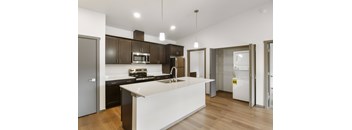 A modern kitchen with a white island and dark brown cabinets.