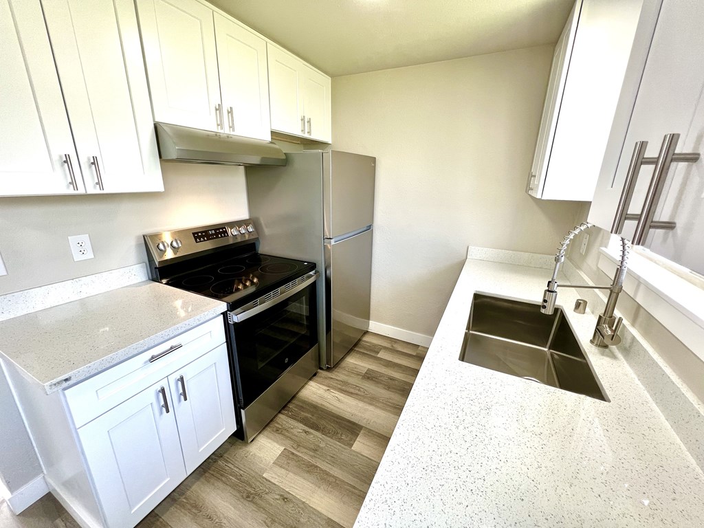 A kitchen with a stove, oven, refrigerator, and sink.