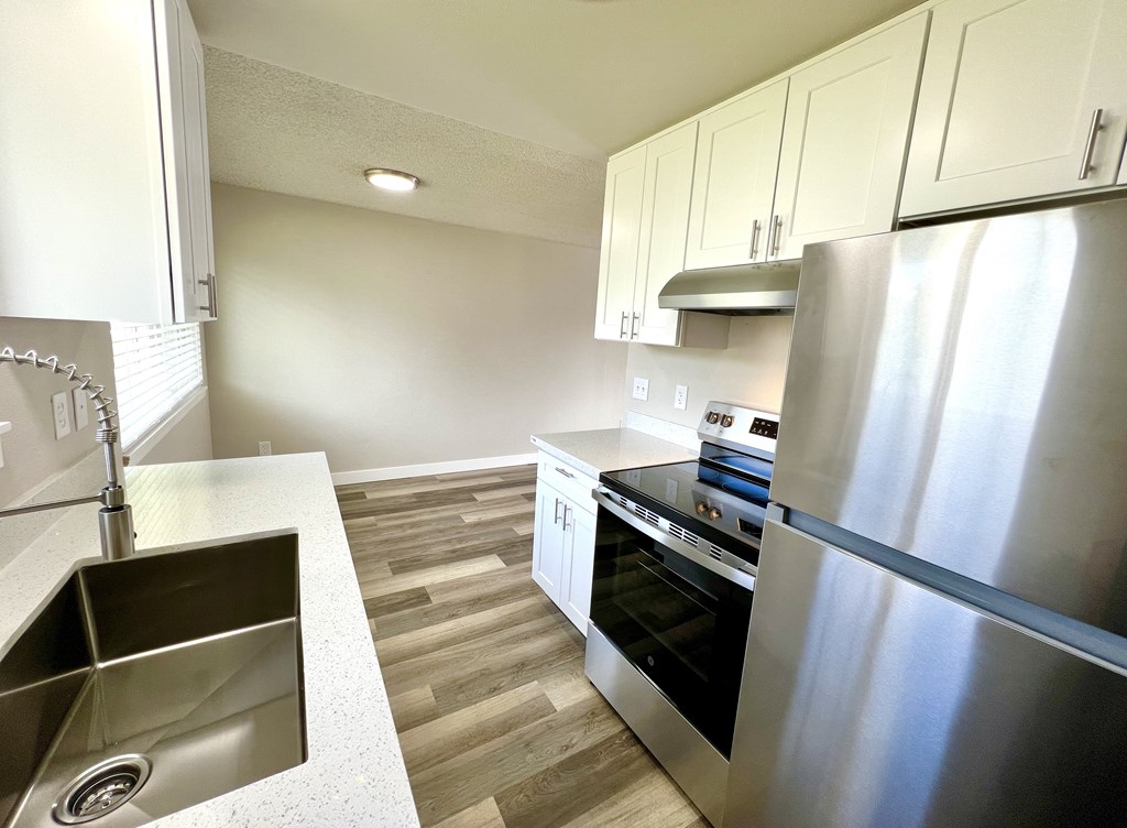 A modern kitchen with a stainless steel refrigerator, oven, and sink.