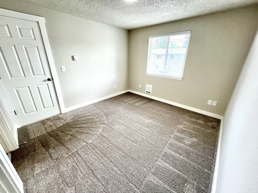 A room with a carpeted floor and a door.
