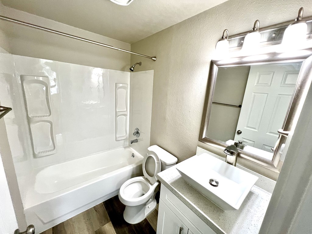 A white bathroom with a toilet, sink, and bathtub.