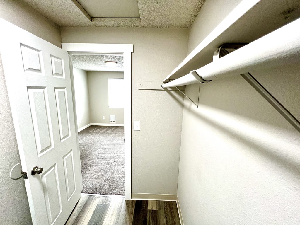 A hallway with a white door and a carpeted floor.