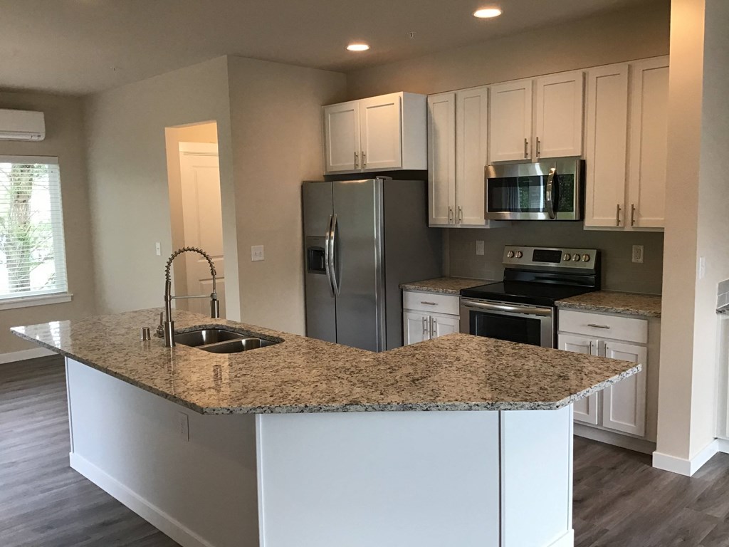 a kitchen with white cabinets and a granite counter top
