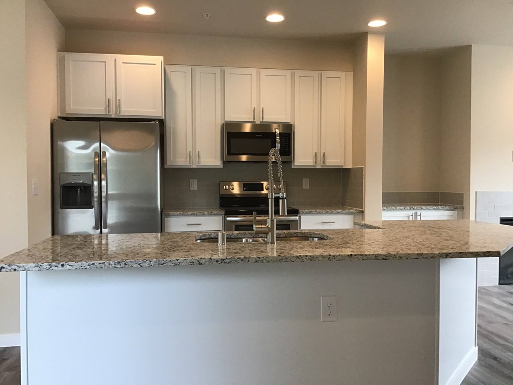 a kitchen with white cabinets and a granite counter top