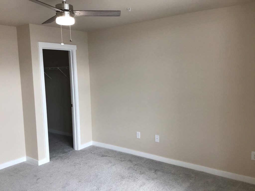 a empty living room with a ceiling fan and a closet