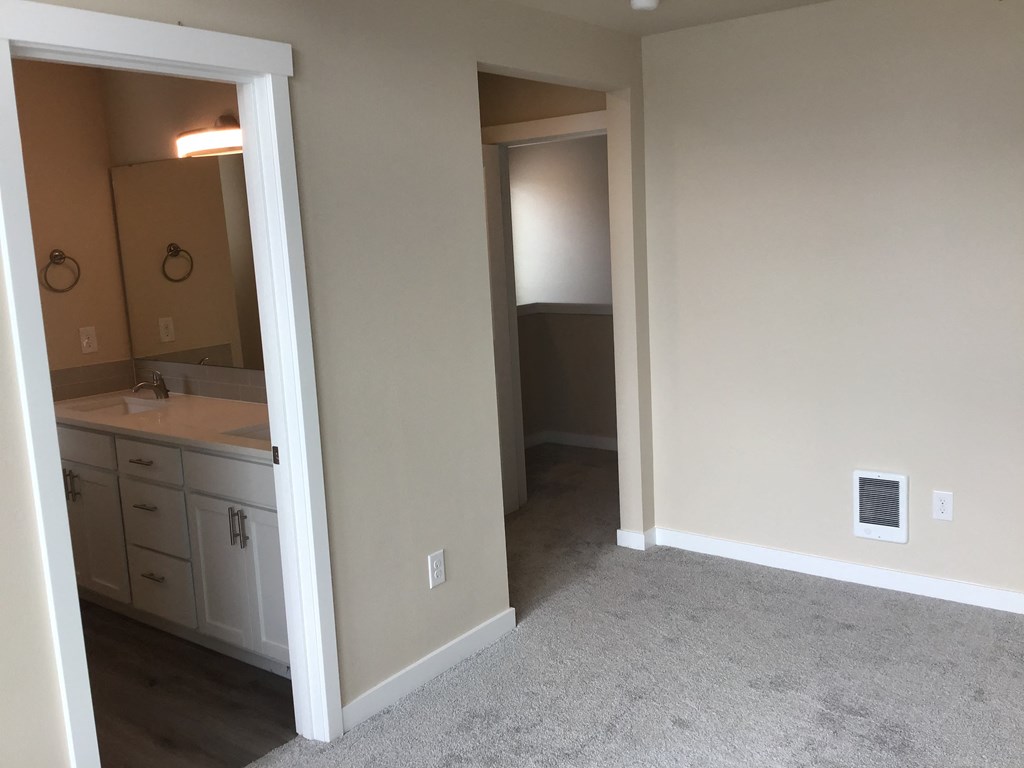 a bedroom and a bathroom with a sink and a mirror