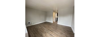 an empty living room with wooden floors and white walls