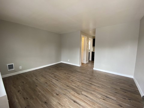 an empty living room with wooden floors and white walls