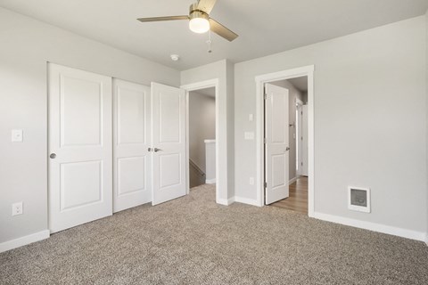 A room with a ceiling fan and carpeted floor.