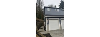 A two-car garage with a grey house in the background.