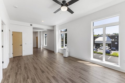 A spacious room with a ceiling fan and large windows.