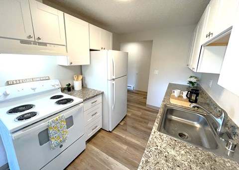 A kitchen with a white stove top oven and a white refrigerator.