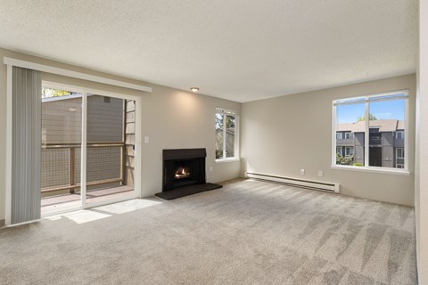 A living room with a fireplace and sliding glass door to balcony in 2 bedroom apartment.