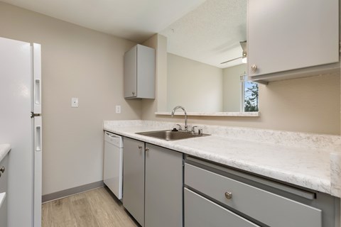 A kitchen with a white counter top and grey cabinets.