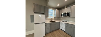 A kitchen with a white refrigerator, a stove, a microwave, and cabinets.