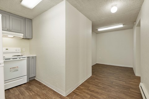 A kitchen with a white stove and wooden floors.