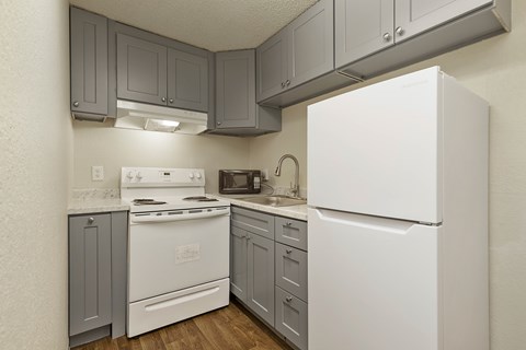 A white refrigerator is in a kitchen with grey cabinets.