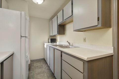 A kitchen with white cabinets and a white fridge.