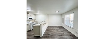 A kitchen with a white counter and a window with blinds.