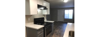 an empty kitchen with white cabinets and a black stove