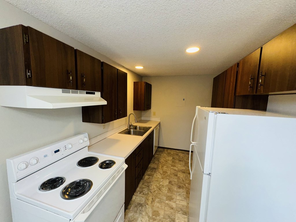 A kitchen with white appliances and brown cabinets.