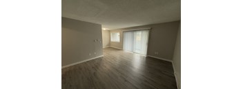 A room with wooden flooring and a window with blinds.