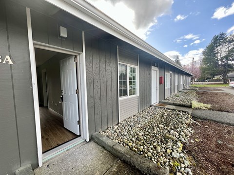 A grey building with a white door is shown.