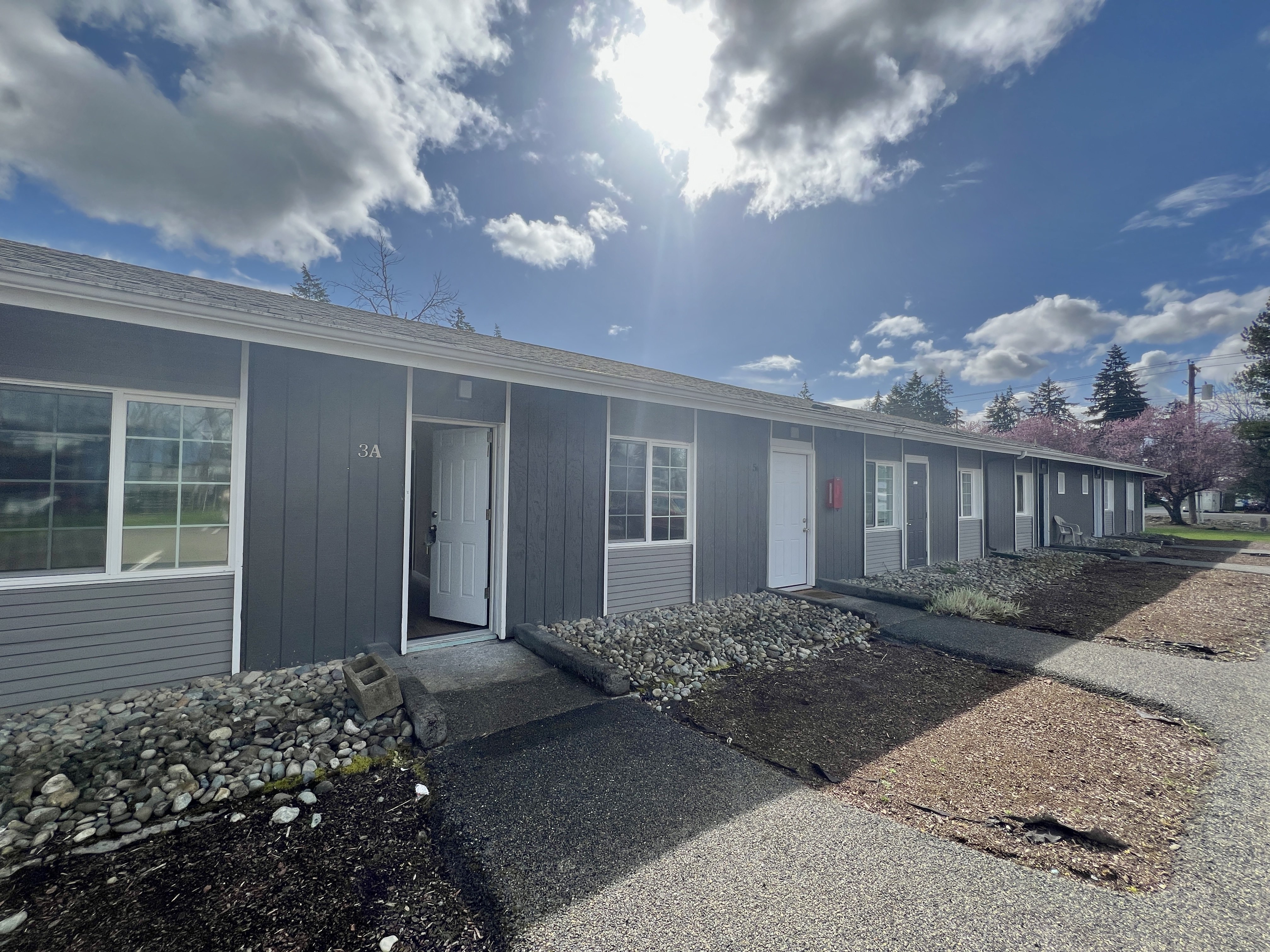 A sunny day at a row of houses with grey siding.