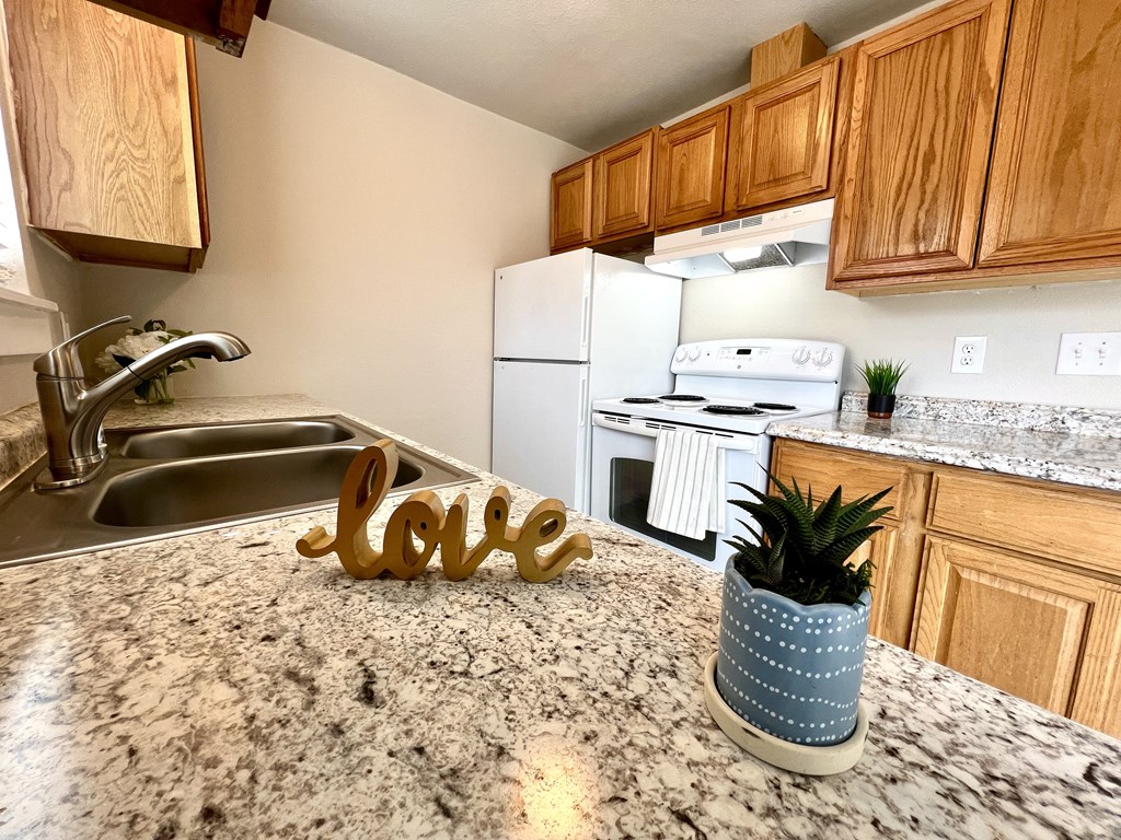 A kitchen with granite countertops and a white fridge.