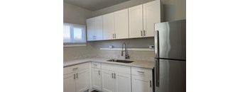 A kitchen with white cabinets and a stainless steel refrigerator.