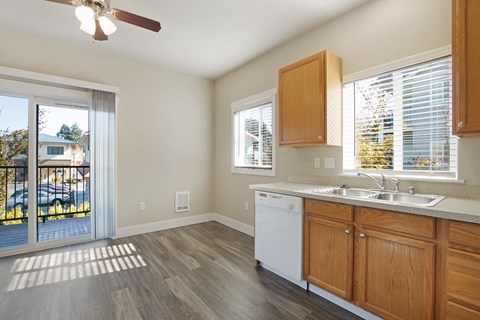 A kitchen with a white dishwasher and wooden cabinets.