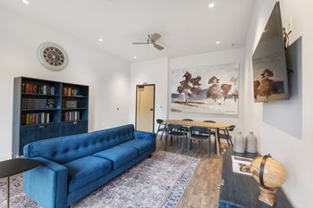 A living room with a blue couch, a bookshelf, and a painting on the wall.