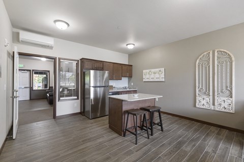 A kitchen with a refrigerator, stove, and bar stools.