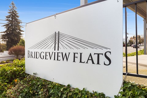 A white sign with the words "Bridgeview Flats" and a logo of a bridge.