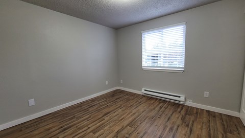 A room with wooden flooring and a window with blinds.