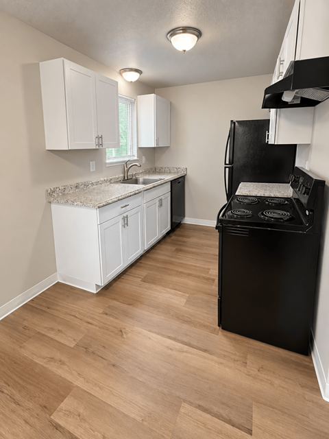 A kitchen with a black fridge and white cabinets.