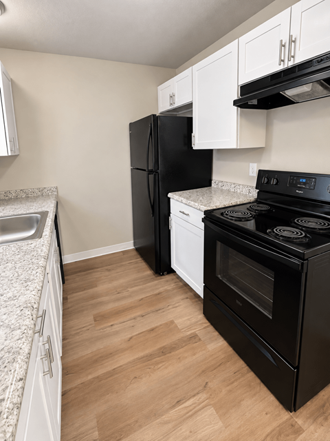 A black stove top oven sits next to a white dishwasher in a kitchen.