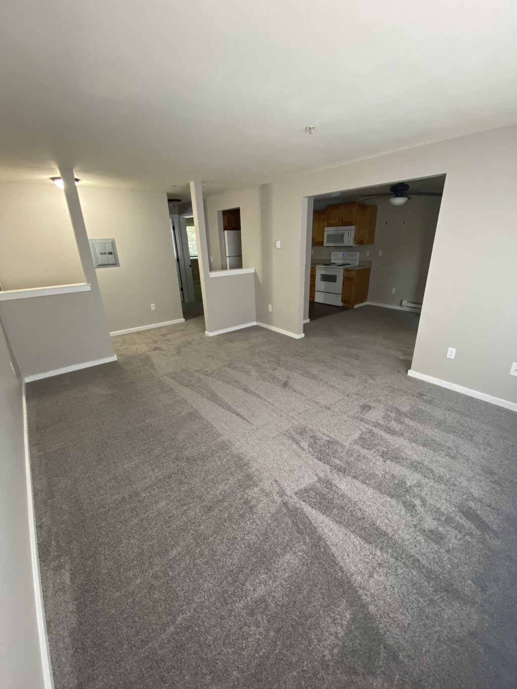an empty living room with carpet and a kitchen
