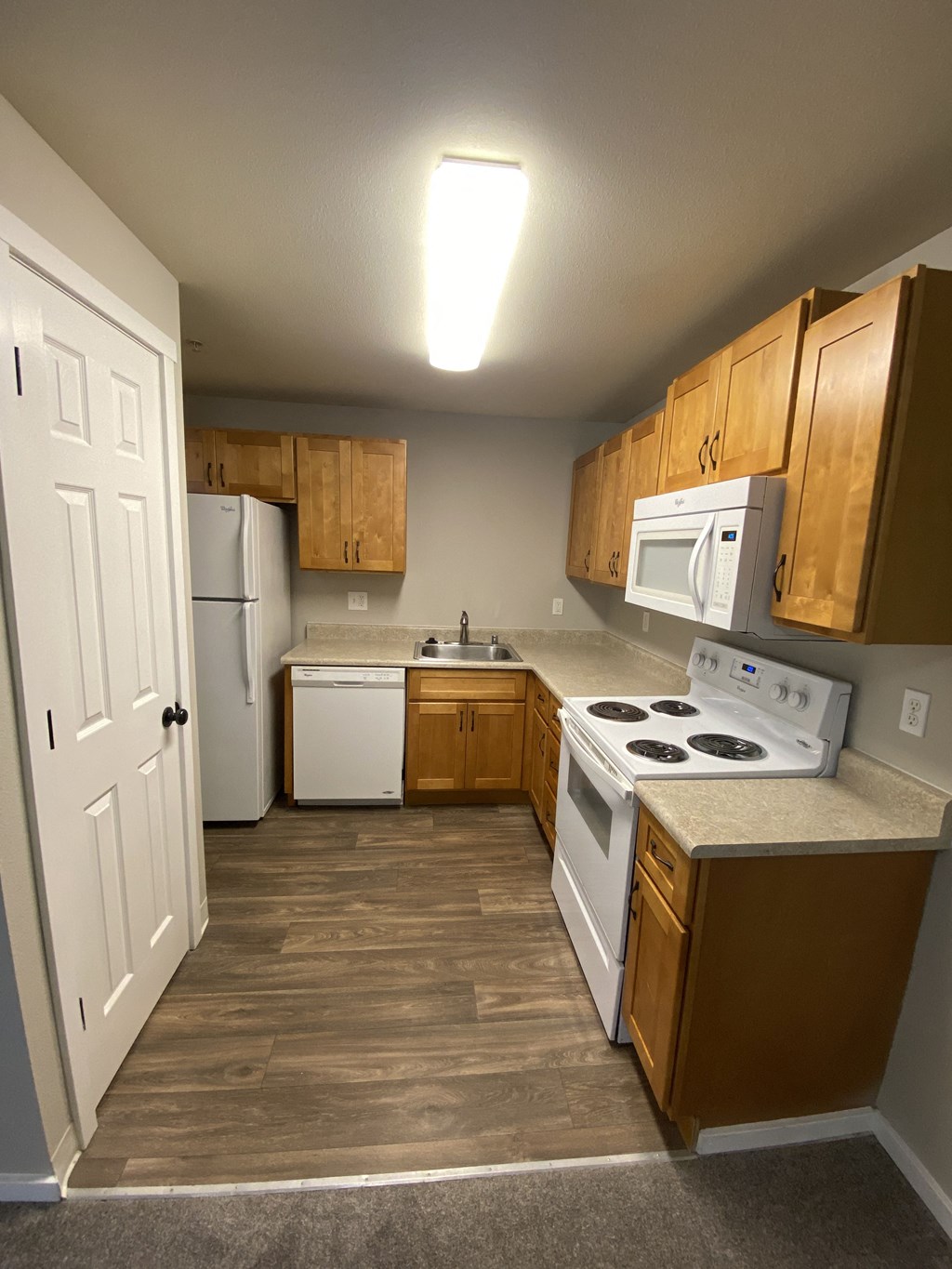 an empty kitchen with wooden cabinets and white appliances