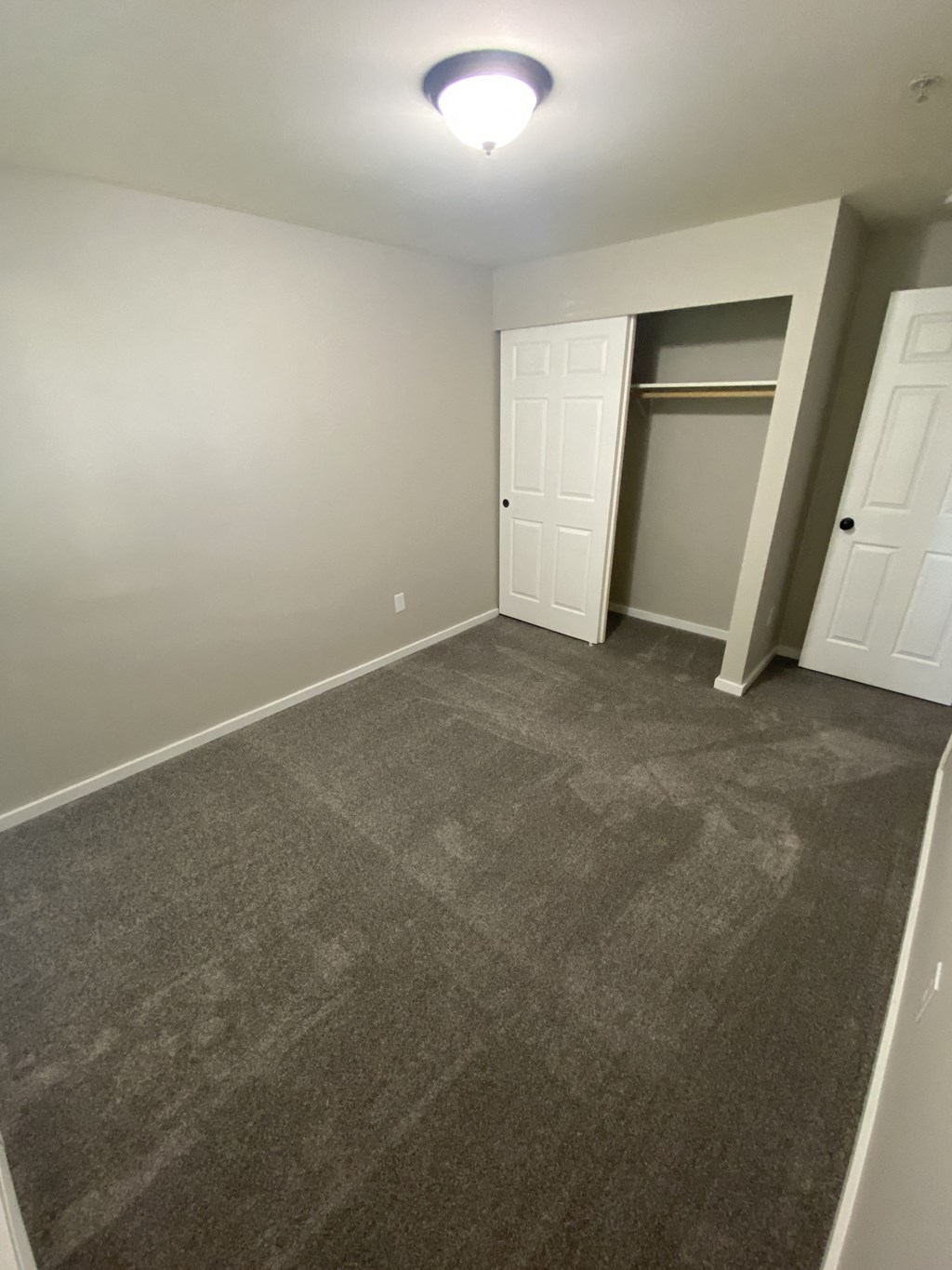 a bedroom with a carpeted floor and a closet