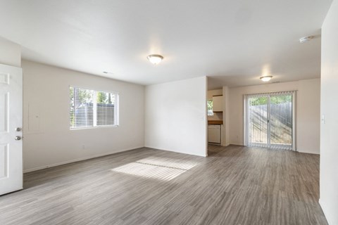 the living room and dining room of an empty house with wood floors and a door