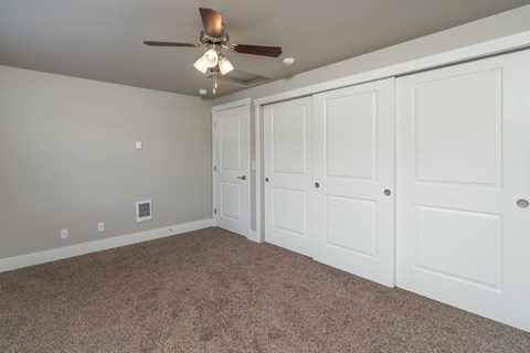 a bedroom with three closets and a ceiling fan