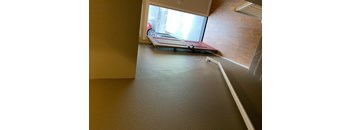 A room with a grey carpet and a red couch.