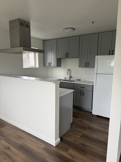 A kitchen with a white counter and grey cabinets.