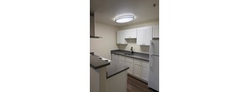 A kitchen with white cabinets and a black counter top.