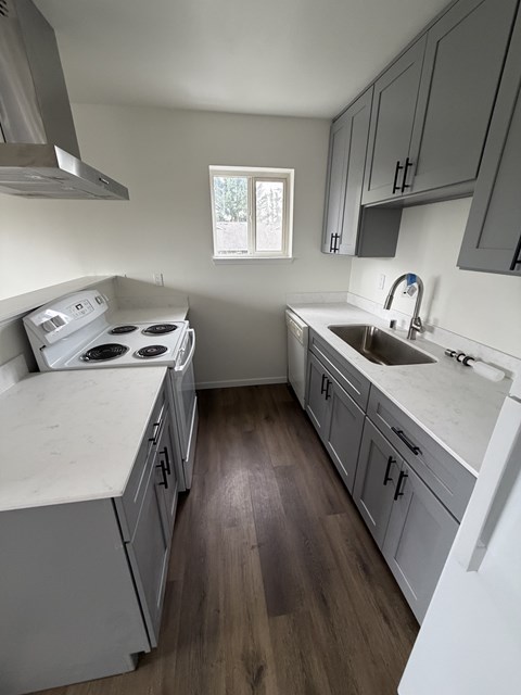 A kitchen with a white stove top oven and a white dishwasher.